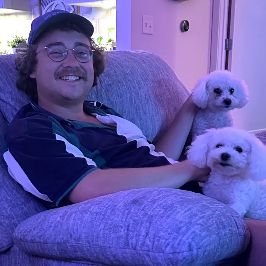 Adam Sweat on the couch with his two white dogs