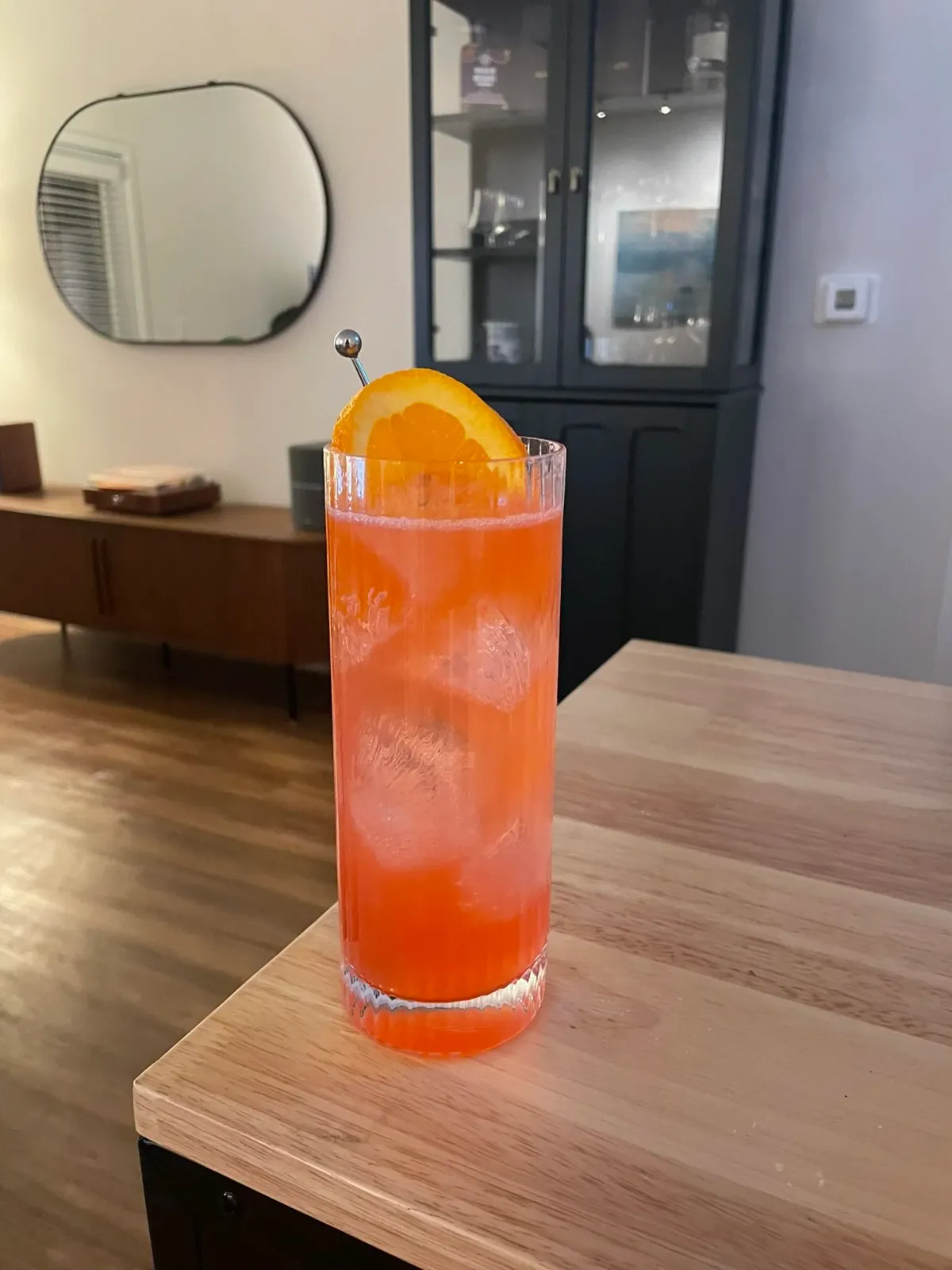 Rome With a View – Campari-orange highball in a fluted Collins glass with an orange wheel, on a wood table
